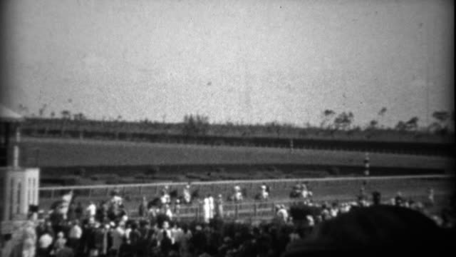 1935: Crowd at horse track race watching horses come out to compete.