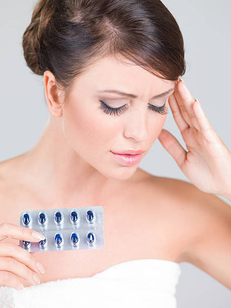 istock Young woman with a headache holding medication 523648097