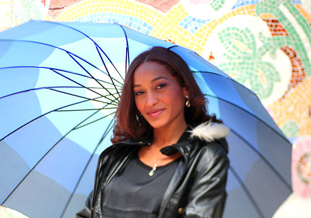 Beautiful mulato woman with umbrella in front of a mosaic, art deco mosaic from Barcelona. 