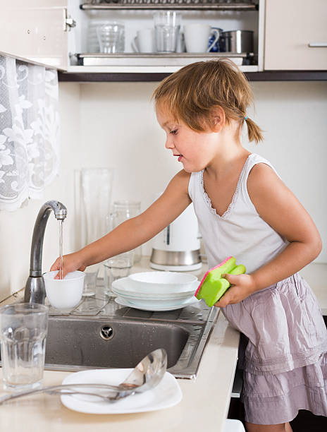 istock Small child cleaning dishes 523650509