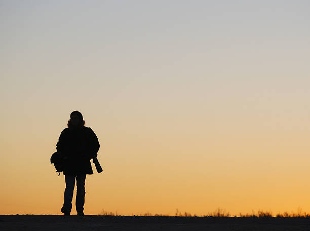 istock Man walking along the road, backlit at sunset 523663411
