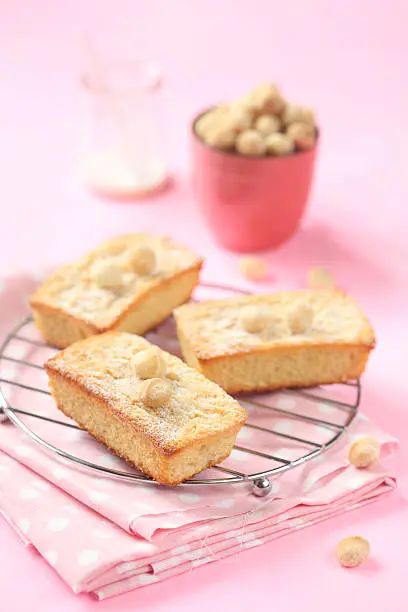 Blondies - White Chocolate Cakes with Macadamia Nuts, on a pink background.