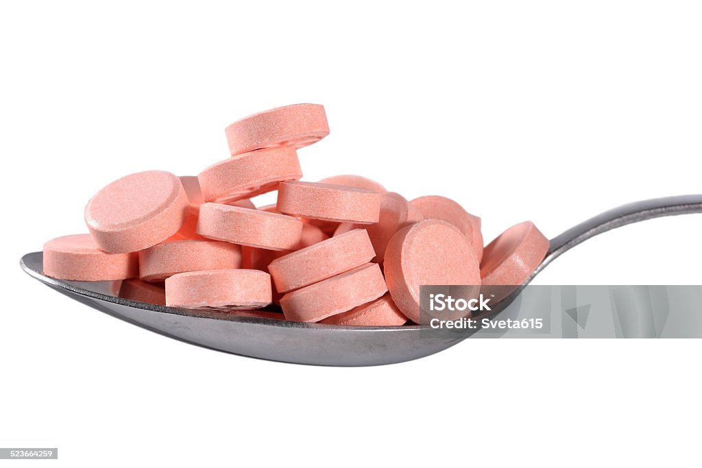 Many pills in spoon Spoon full of pills on a white background Antibiotic Stock Photo