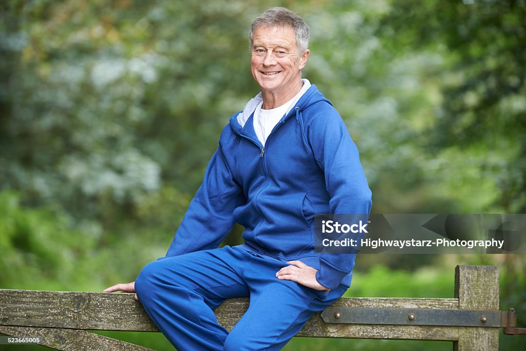 Senior Man Resting Whilst Exercising In Countryside Tracksuit Stock Photo