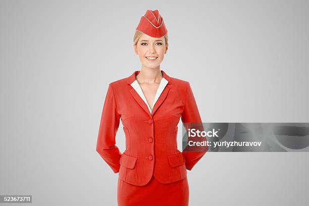 Charming Stewardess Dressed In Red Uniform On Gray Background Stock Photo - Download Image Now