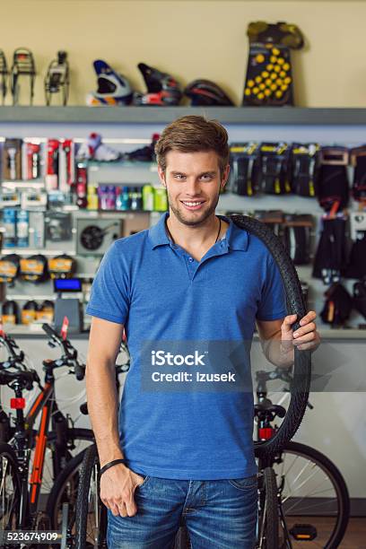 Sales Clerk With Bike Tire In A Sport Store Stock Photo - Download Image Now - Manager, Sports Shop, 20-24 Years