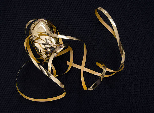istock Gold gift wrap tape, ribbon over black fabric background. 523676599