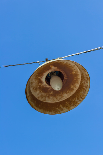 single vintage street light hanging under clear blue sky