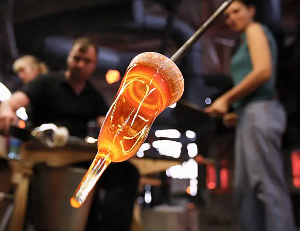 Glass furnace. Man holding a red-hot glass