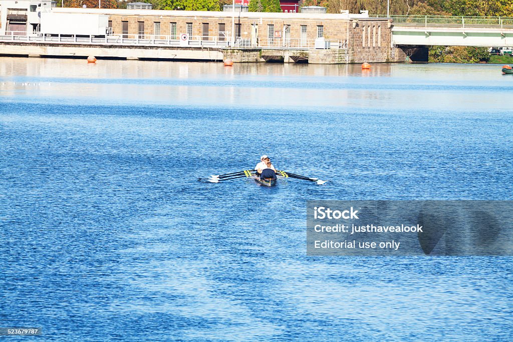 Rowing on Ruhr Essen, Germany - October 19, 2014: Men are rowing in sports rowboat on river Ruhr in autumn sunshine at morning. Aerial view over river from railway bridge. In background is dam and bridge over Ruhr in Essen Kettwig. Adult Stock Photo