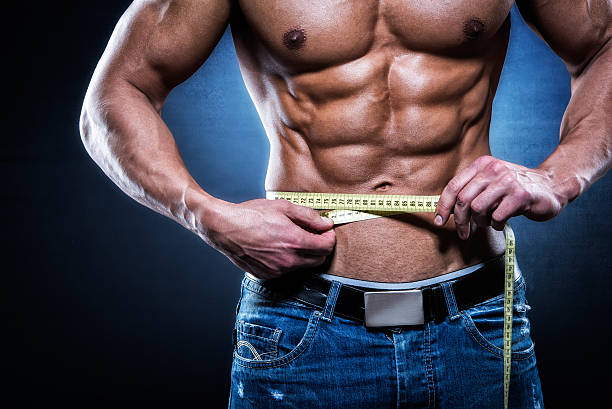 istock Muscular man holding tape measure 523681177