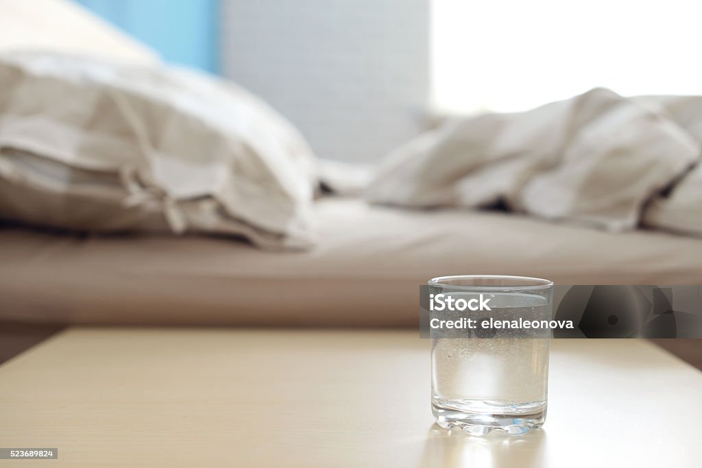 Glas von Wasser auf dem Nachttisch im Schlafzimmer - Lizenzfrei Nachttisch Stock-Foto