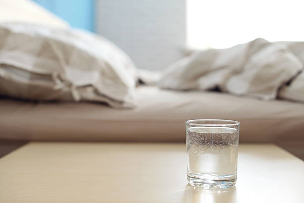 bicchiere di acqua di notte tavolo in camera da letto - comodino foto e immagini stock