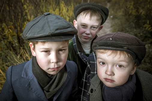 Portrait of three serious little boys bullies on urban wasteland