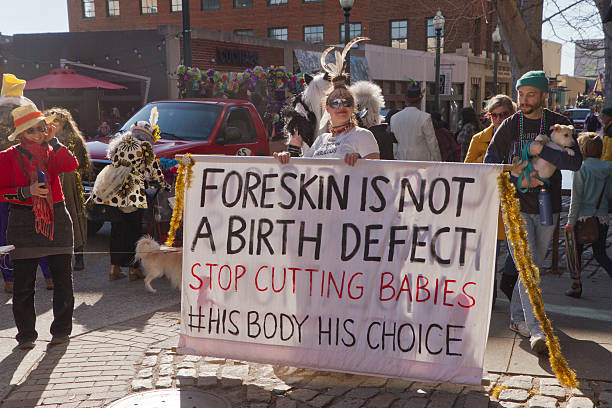 Foreskin Is Not a Birth Defect Asheville, North Carolina, USA - February 7, 2016: Costumed young woman holds large sign about circumcision saying "Foreskin is not a birth defect" in the Mardi Gras parade on February 7, 2016 in downtown Asheville, NC circumcision surgery stock pictures, royalty-free photos & images