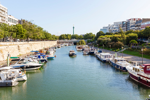Large view of Port de l'Arsenal in Paris, France. Many boats on this part of the Seine with the Bastille monument on the background.