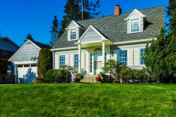 Quaint Cape Cod Style House Photo of a quaint American Cape Cod Style home on a sunny day with clear blue sky and green grass. cape cod stock pictures, royalty-free photos & images