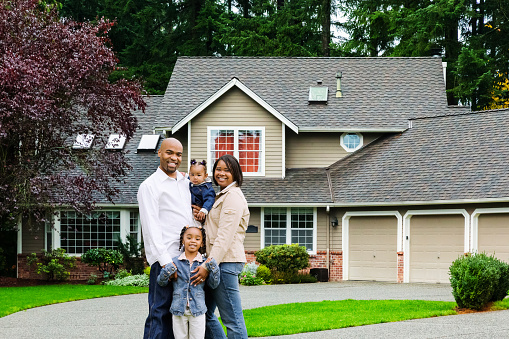Photo of a happy African American family of four standing in front of their home.