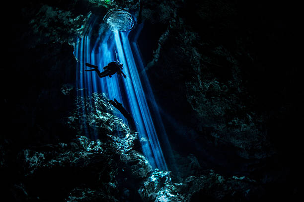 Rays of light in dark underwater cave Scuba diver exploring the underwater cenotes in Mexico near Puerto Aventuras. Caves are dark and the light always gives different amazing ambient underwater. puerto aventuras stock pictures, royalty-free photos & images