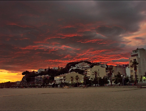 stormy sky red and yellow on a sunset on the beach of Canet de Mar and over the village