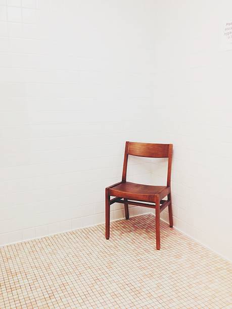 Wooden chair in public bathroom with white tile walls and pink tile floor