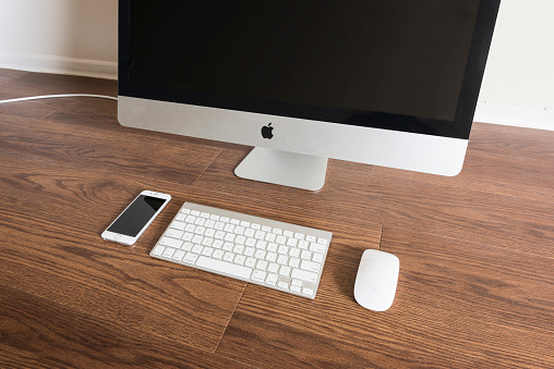 Toronto, Canada - March 25, 2016: iPhone 6s placed next to iMac 27inch monitor, magic keyboard and mouse. The iPhone 6s is the latest apple device released on September 19, 2015 by Apple.