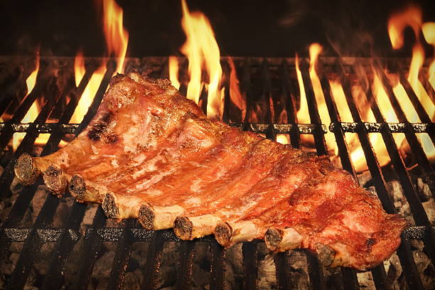 wieprzowina powrót dziecka lub żeberek na bbq grill z płomieni - rubbing spice rib barbecue zdjęcia i obrazy z banku zdjęć