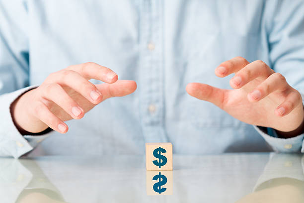 istock Man holding protective hands above wooden cube with dollar sign 523709267