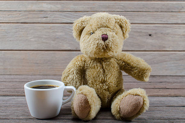 istock Bear drinking coffee on a wooden table in the garden. 523713249