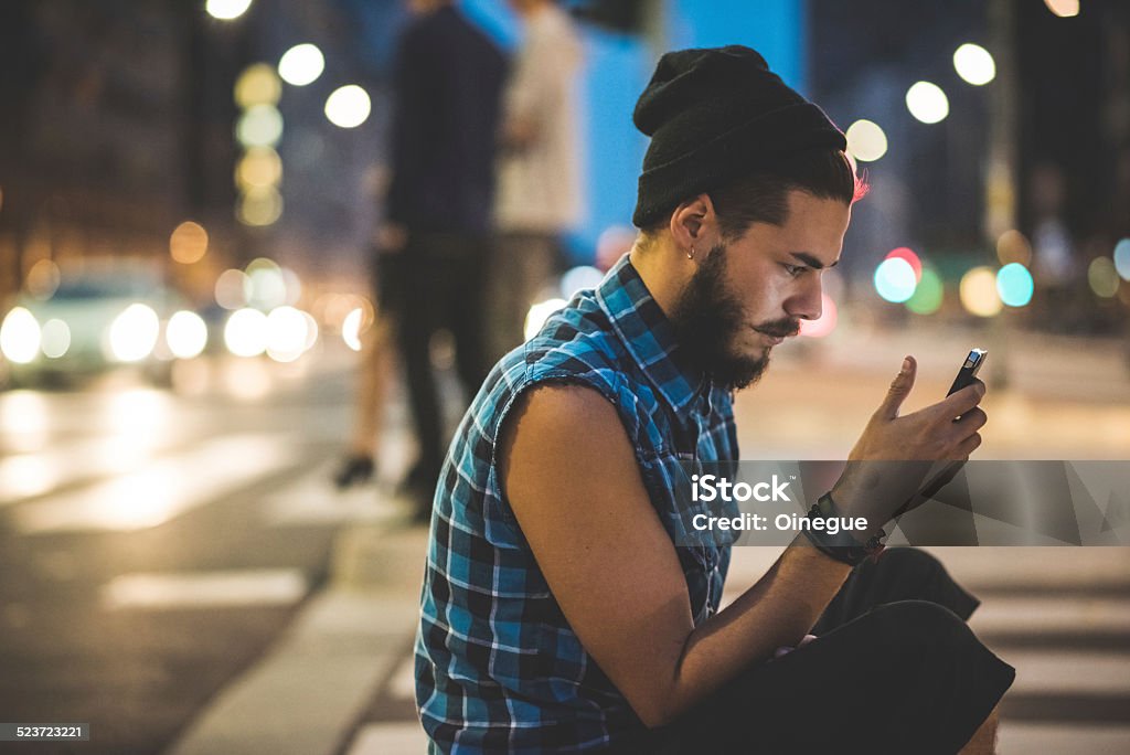 young handsome bearded hipster man young handsome bearded hipster man using smartphone and listening music with earphones in the city Adult Stock Photo