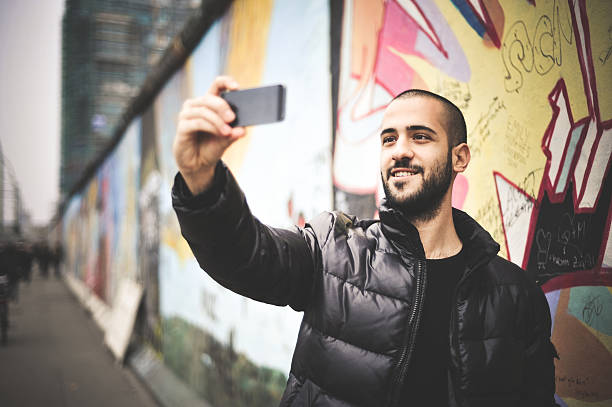 Young Man Taking Selfie In Front Of The Berlin Wall stock photo