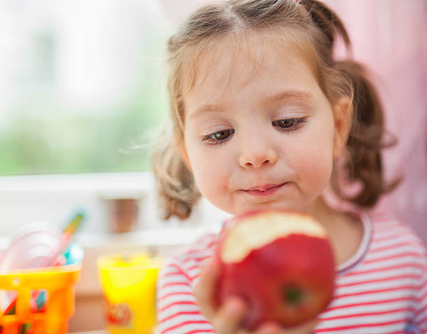 petite jolie fille mangeant une pomme - apple missing bite fruit red photos et images de collection