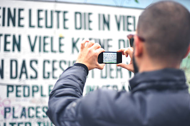 Young man taking a photo of Berlin Wall