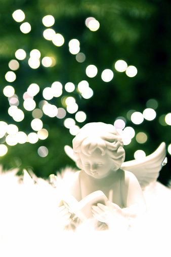 White angel figurine with Christmas tree and blur lights in the background