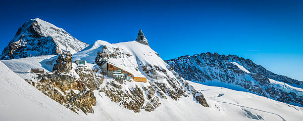Alps cable car station observatory high in snowy mountains Switzerland Clear blue high altitude skies over the deep winter snow on the Jungfraujoch and Aletsch Glacier looking towards the iconic dome of the Sphinx Observatory and tourists at the Jungfraubahn Top of Europe building, Bern, Switzerland. ProPhoto RGB profile for maximum color fidelity and gamut. grindelwald photos stock pictures, royalty-free photos & images