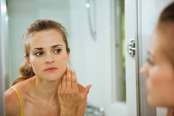 istock Young woman checking her face in mirror 523750757