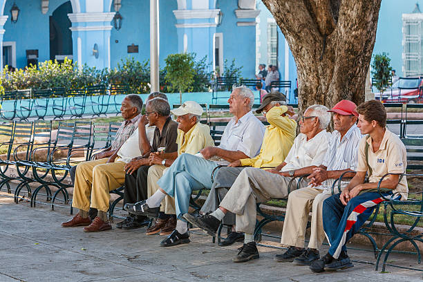 Sancti Spiritus, Cuba - February 24, 2007: Group of seniors resting in Parque Serafin Sanchez, the central square of the city, surrounded by benches and colonial palaces.