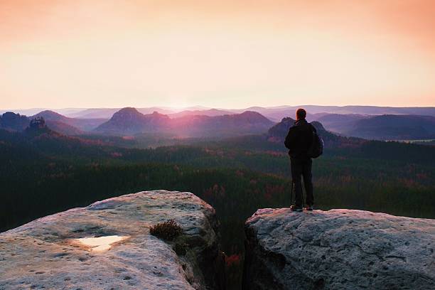 istock Guide on rock with pole in hand. Hiker sporty backpack 523764258