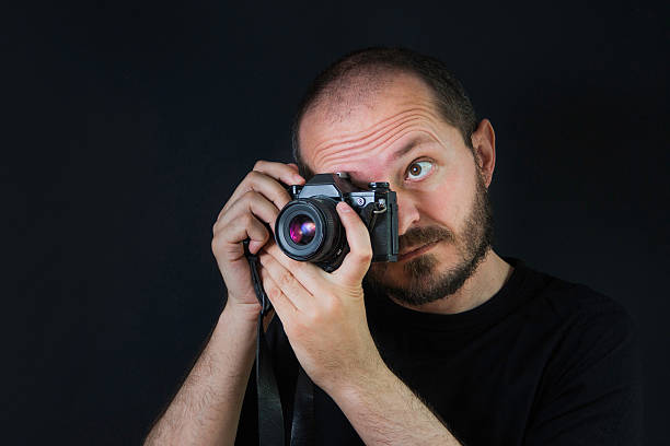 istock Man on black background holding analog camera and taking photos 523766694