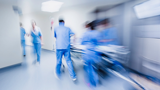 Doctors and nurses pulling hospital trolley,