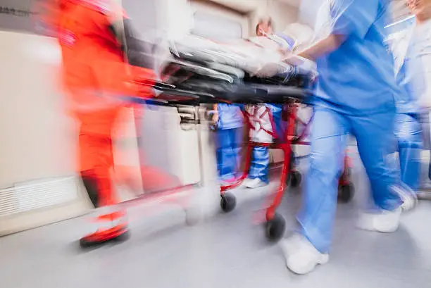 Paramedics and nurse pulling hospital trolley,