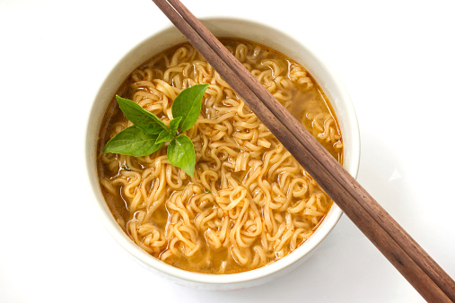 Instant noodle with basil leaf in a white bowl. On whit background.