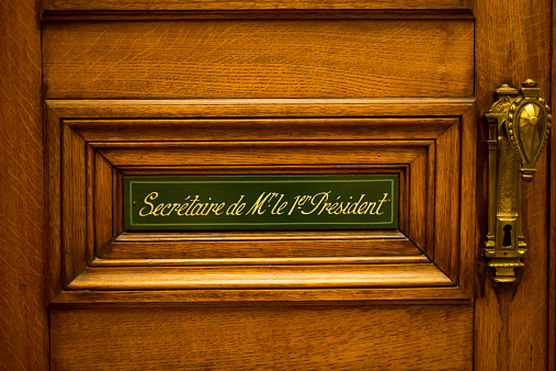 Classical style wooden door with sign saying: Secretary of the president written in French. Courthouse in Brussels. Belgium.