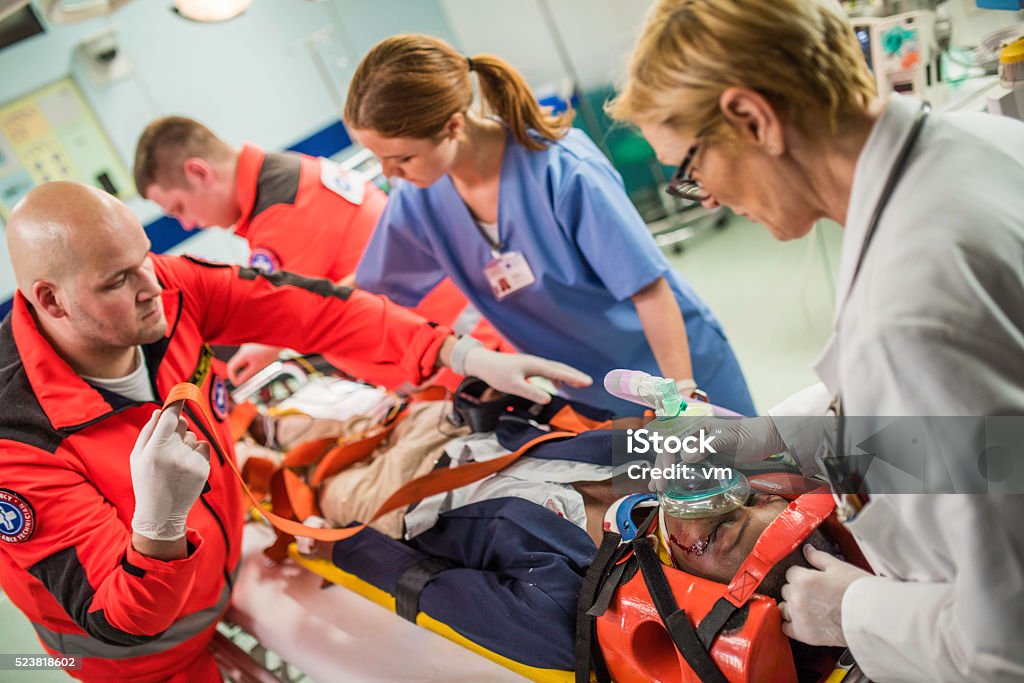 Paramedics and doctors in emergency room Paramedics, female doctor and nurse with injured patient in emergency room. Emergency Room Stock Photo