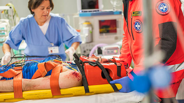 Paramedics and nurse in emergency room Paramedic and nurse with injured young female patient in emergency room. hospital emergency sign stock pictures, royalty-free photos & images