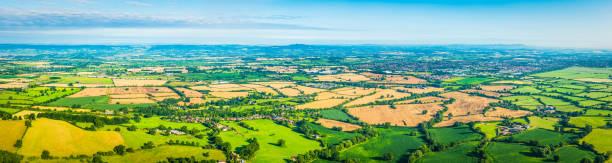 istock Aerial panorama over green patchwork landscape farms fields rural villages 523820996