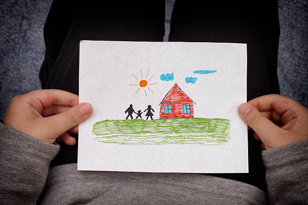 istock Child holds a drawn house with family 523824472