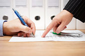 business woman is pointing where to sign on document,