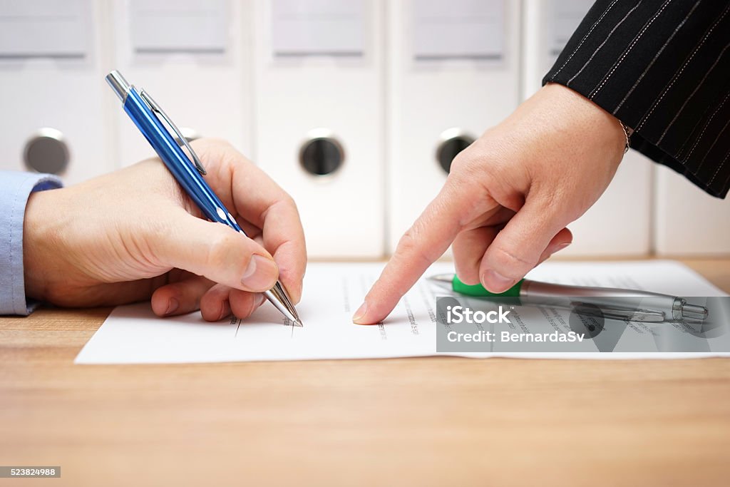 business woman is pointing where to sign on document, business woman is pointing where to sign on document, with documents in background Quitting a Job Stock Photo