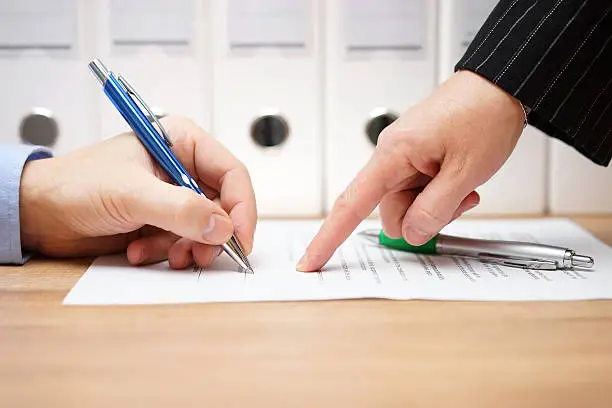 Photo of business woman is pointing where to sign on document,